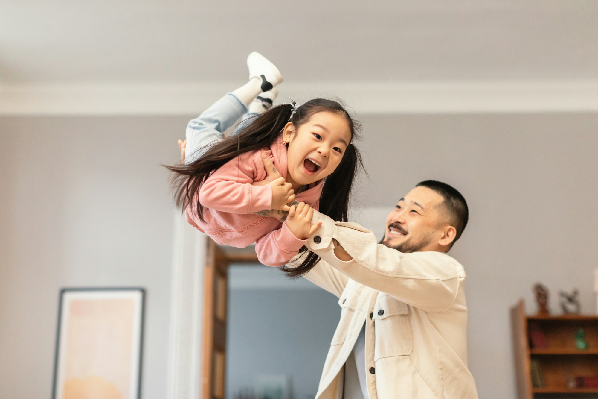 Happy Korean Father Lifting Kid Daughter In Air Playing Indoor